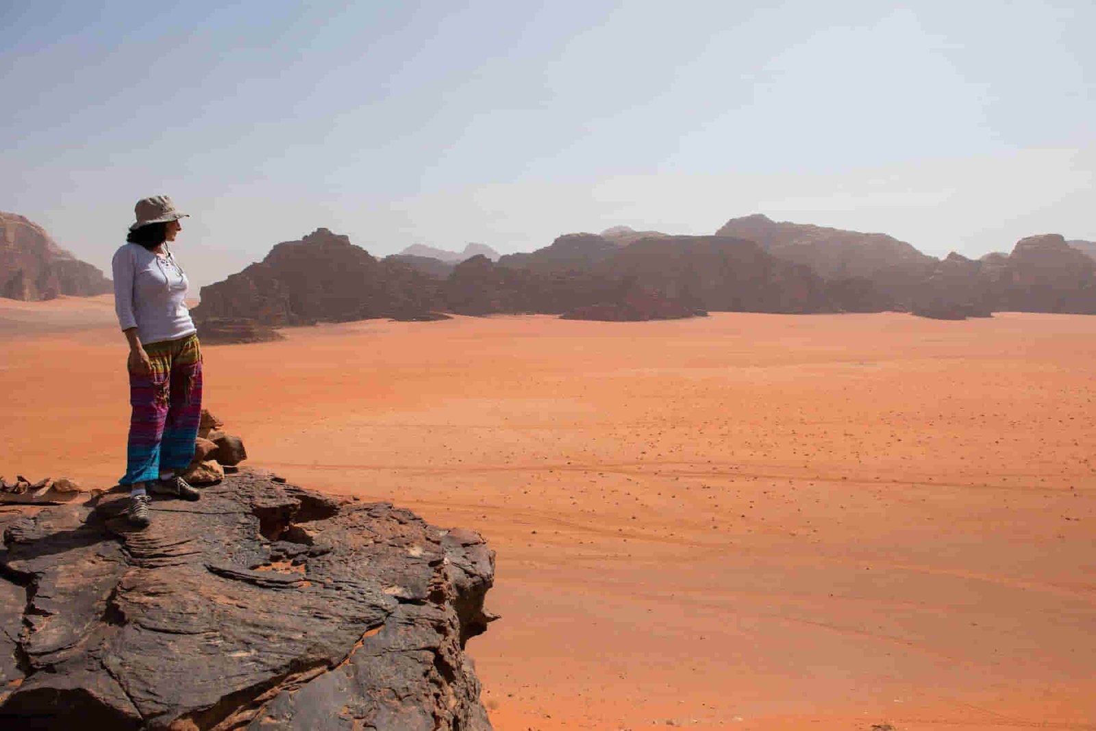 faq : Trekker woman enjoying desert landscape on a rocky height. Wadi Rum, Jordan